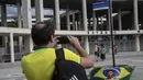 Seorang pria mengambil foto plang dengan nama baru jalan yang mengelilingi stadion Maracana, yang sekarang akan dikenal sebagai King Pele Avenue di Rio de Janeiro, Brasil, 4 Desember 2022. Perubahan nama tersebut sebagai penghargaan untuk legenda sepak bola Brasil, Edson Arantes do Nascimento atau lebih dikenal sebagai Pele. (AP Photo/Bruna Prado)