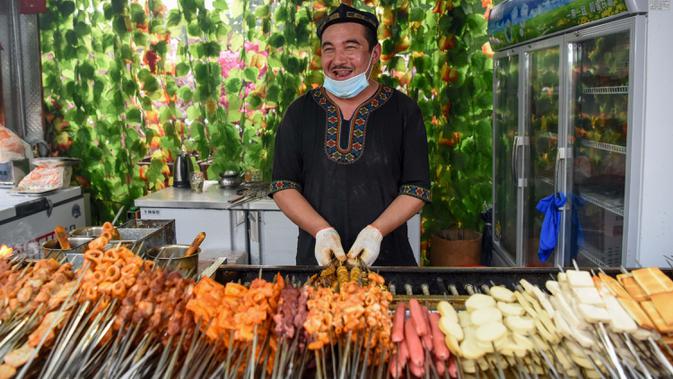 Seorang pedagang membuat barbeku di Grand Bazaar Food Street di Urumqi, ibu kota Daerah Otonom Uighur Xinjiang, China barat laut, pada 4 Juli 2020. (Xinhua/Ding Lei)