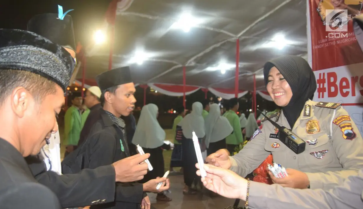 Seorang polwan menggelar aksi keprihatinan dengan membagikan lilin kepada peserta tablig akbar di Simpang Lima, Kota Semarang, Minggu (13/5). Aksi menyalakan lilin dan doa bersama digelar untuk korban teror bom gereja di Surabaya. (Liputan6.com/Gholib)