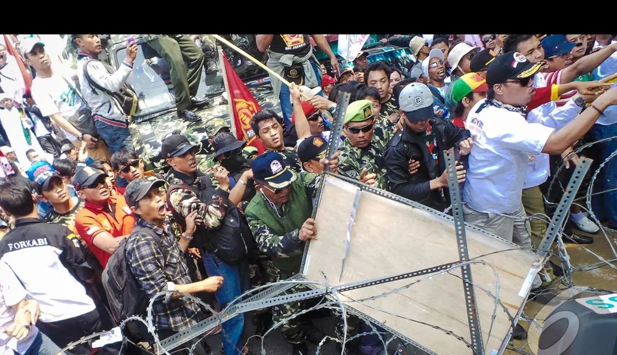 Massa Prabowo nekat menerobos kawat berduri dengan cara merusaknya dengan aneka benda, Jakarta, Kamis (21/8/2014) (Liputan6.com/Faizal Fanani)
