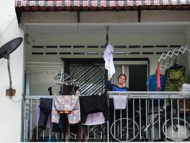 Ibu tunggal Tilda Kalaivani melambaikan kemeja yang digunakan sebagai bendera putih di apartemen sewaannya di Kuala Lumpur pada 6 Juli 2021. Akibat lockdown nasional, banyak keluarga berpenghasilan rendah yang terdampak oleh pandemi COVID-19 semakin kesulitan dalam menjalani hidup. (Mohd RASFAN/AFP)