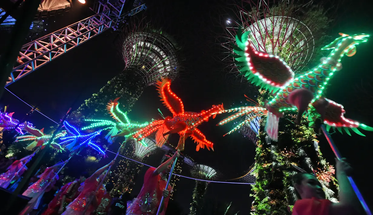 Sejumlah wanita membawakan tarian phoenix yang dihiasi dengan lampu warna-warni di Gardens by the Bay, Singapura (4/2). Ornamen burung phoenix terlihat cantik dengan cahaya warna-warni. (AFP/Roslan Rahman)