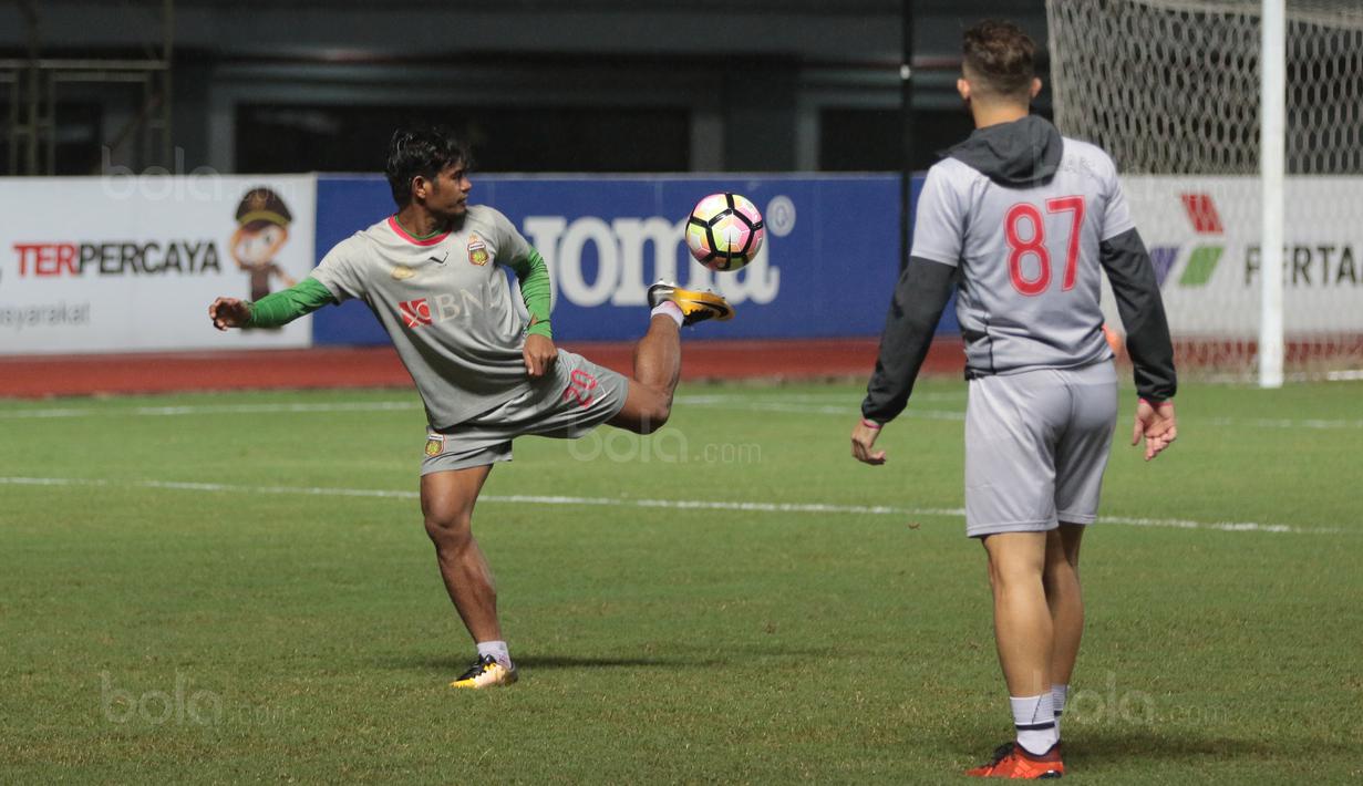 Pemain Bhayangkara FC, Ilham Udin (kiri) dan Ilija Spasojevic (kanan) menguji lapangan basah sebelum sesi latihan di Stadion Patriot Bekasi, Sabtu (11/11/2017). Latihan tersebut jelang melawan Persija. (Bola.com/Nicklas Hanoatubun)