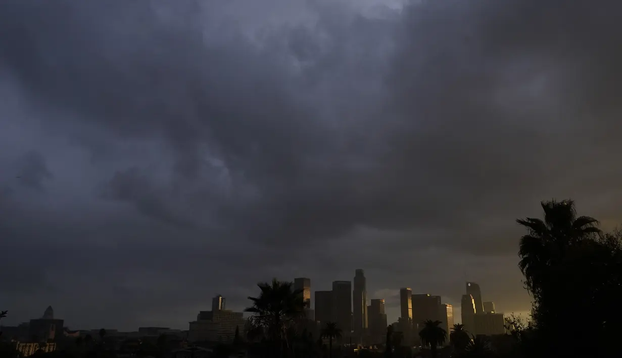 Awan tebal bergerak di atas pusat kota Los Angeles (13/12/2021). Badai itu akan membawa kelembapan yang sangat dibutuhkan ke wilayah yang lebih luas yang dilanda kekeringan yang menurut para ilmuwan disebabkan oleh perubahan iklim. (AP Photo/Damian Dovarganes)