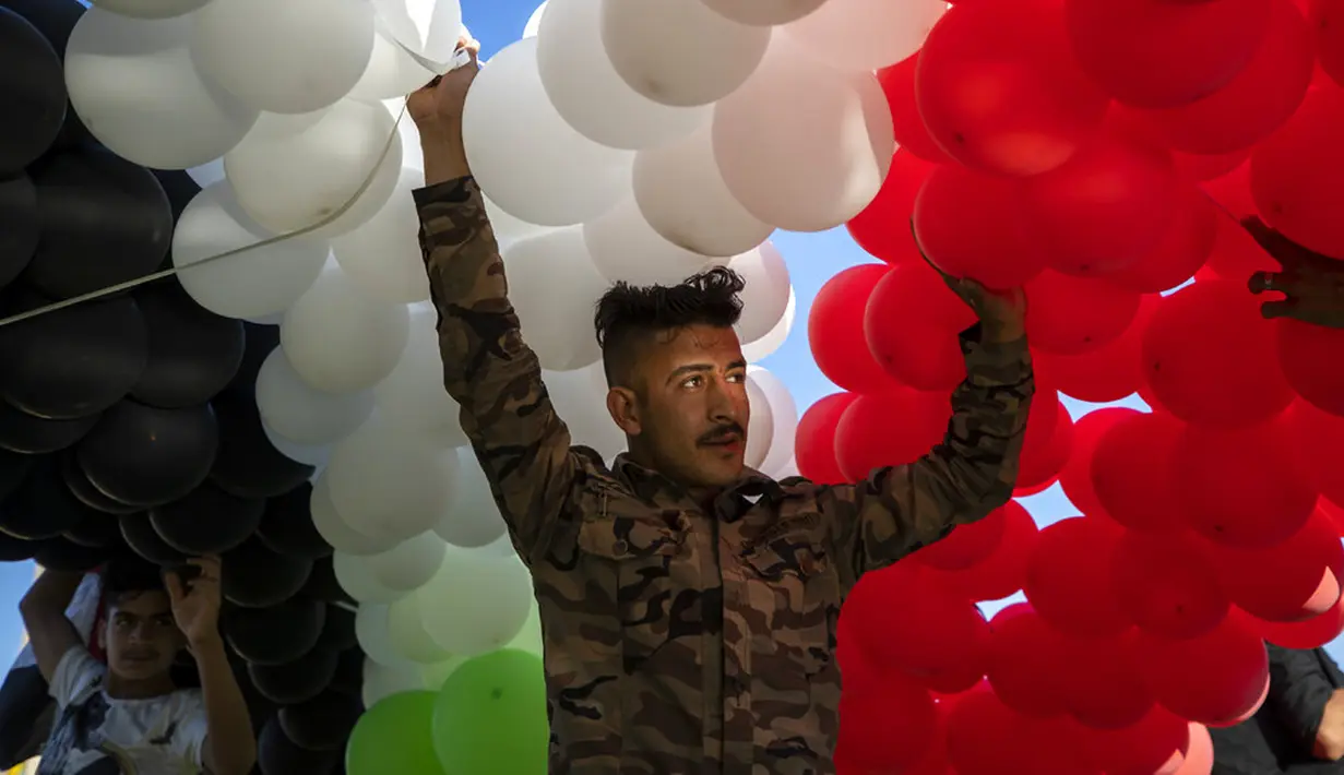 Seorang pendukung Presiden Suriah Bashar Assad bersiap melepas ratusan balon berwarna bendera Suriah pada pertemuan di Omayyid Square, Damaskus, Suriah, Minggu (23/5/2021). Pemilihan presiden di negara yang dilanda perang itu akan diadakan pada 26 Mei. (AP Photo/Hassan Ammar)