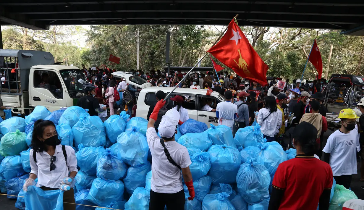 Para pengunjuk rasa mengumpulkan sampah saat mereka mengambil bagian dalam demonstrasi menentang kudeta militer di Yangon (12/2/2021). (AFP/STR)