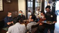 Pramusaji menggunakan pelindung wajah, masker dan sarung tangan saat melayani pelanggan di The Atjeh Connection Coffee and Resto, Jakarta, Senin (8/6/2020). Tempat ini siap menerapkan protokol kesehatan dalam menerapkan tatanan kehidupan baru atau ‘new normal’. (Liputan6.com/Faizal Fanani)