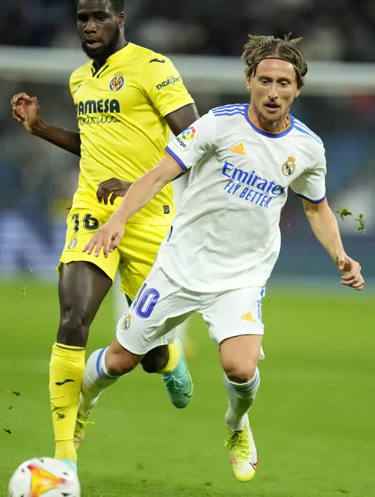 Gelandang Real Madrid Luka Modric terjatuh saat berebut bola dengan penyerang Villarreal Boulaye Dia pada jornada ketujuh La Liga Spanyol di Santiago Bernabeu, Minggu (26/9/2021) dini hari WIB. Real Madrid hanya mampu bermain imbang tanpa gol kala menjamu Villarreal. (AP Photo/Manu Fernandez)
