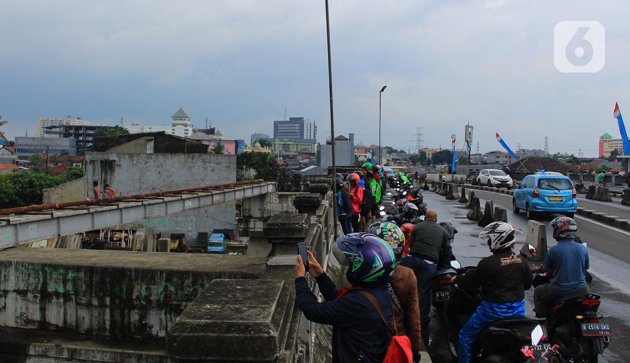 Sejumlah pengendara menepi untuk melihat kondisi kali Ciliwung dan beberapa anak melakukan aksi lompat dari atas jembatan Ciliwung Kalibata, Jakarta, Selasa (25/2/2020). (merdeka.com/magang/Muhammad Fayyadh)