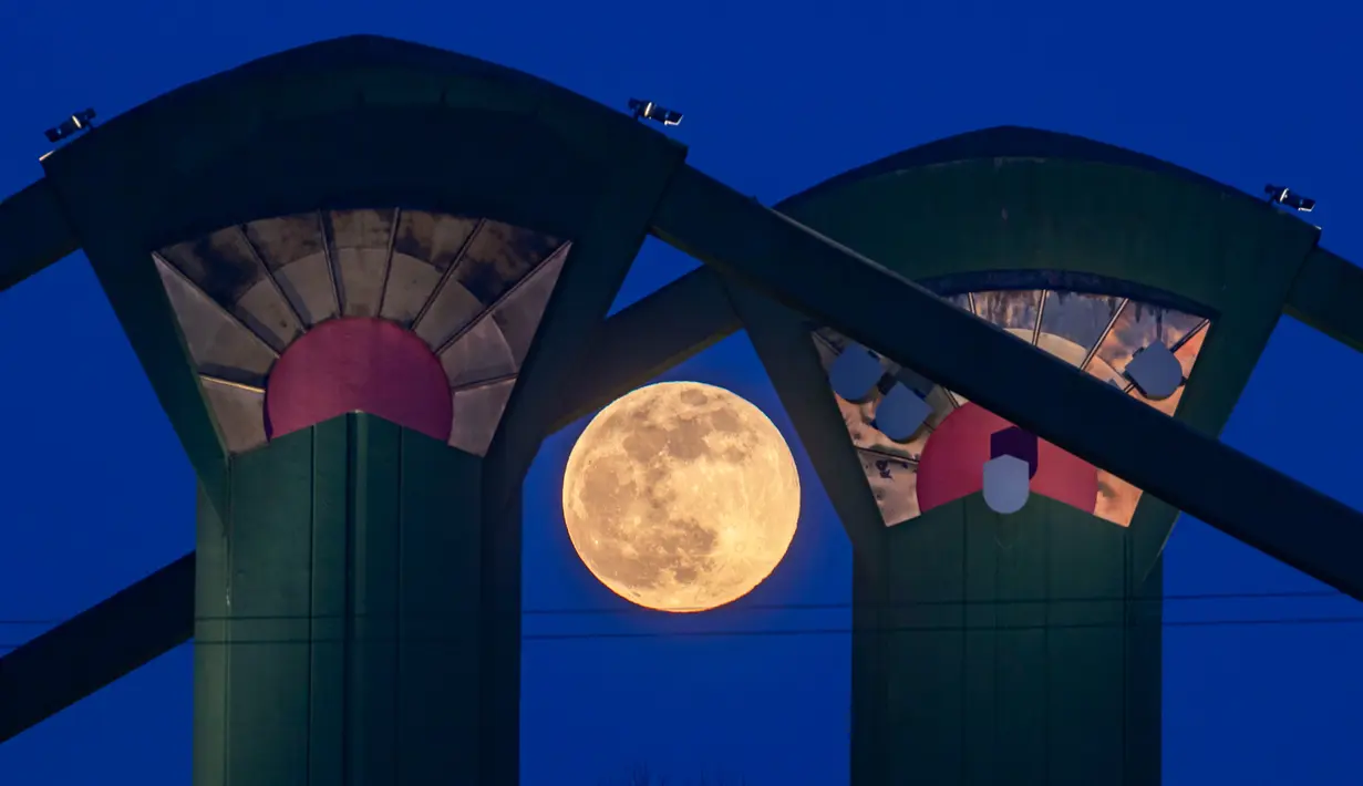 Fenomena super snow moon terlihat di antara Jembatan Floesser, Frankfurt, Jerman, Selasa (19/2). Super snow moon membuat langit berada di paras paling terang sepanjang tahun. (Frank Rumpenhorst/dpa via AP)