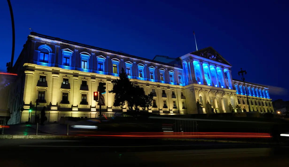 Kendaraan melewati Parlemen Portugal yang diterangi warna bendera Ukraina untuk menandai peringatan satu tahun invasi Rusia ke Ukraina di Lisbon, Portugal, 23 Februari 2023. (AP Photo/Armando Franca)