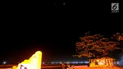 Warga menyaksikan pemandangan planet Mars berdampingan dengan gerhana bulan total terlihat di Karang Hawu, Pelabuhan Ratu, Sukabumi, Sabtu (28/7) dini hari. Fenomena alam ini menjadi gerhana Bulan paling lama Abad 21.  (Merdeka.com/Arie Basuki)