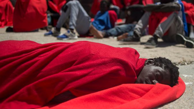 Seorang imigran beristirahat menggenakan selimut setelah perahu karet yang membawa 135 orang diselamatkan oleh penjaga pantai Spanyol di Mediterania di pelabuhan Tarifa, Spanyol (24/7). (AFP Photo/Jorge Guerrero)