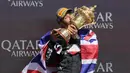 Pembalap Mercedes, Lewis Hamilton mencium piala saat merayakan kemenangannya di Formula 1 GP Inggris 2024 yang berlangsung di Sirkuit Silverstone, Inggris, Minggu (08/07/2024). (AFP/Benjamin Cremel)