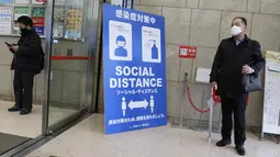 Warga memakai masker untuk melindungi dari penyebaran virus corona menjaga jarak sosial di pintu masuk sebuah gedung di Tokyo (8/3/2021). Pemerintah Jepang memperpanjang keadaan darurat di wilayah Tokyo hingga 21 Maret karena sistem medis masih disaring oleh pasien COVID-19. (AP Photo/Koji Sasahara)