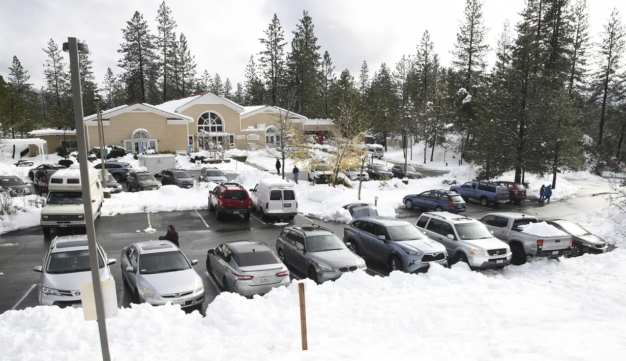 Orang-orang menggunakan tempat parkir Perpustakaan Madelyn Helling untuk memanfaatkan pusat pengisian dan penghangatan perangkat Palang Merah Amerika di Kota Nevada, California, Selasa (28/12/2021). (Elias Funez/The Union via AP)