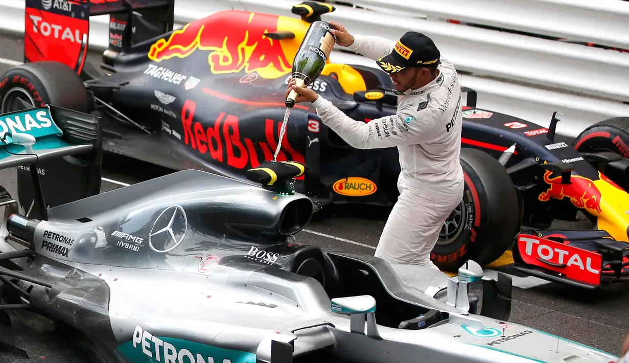 Pembalap Mercedes F1 Lewis Hamilton menyemprotkan sampanye ke mobilnya saat merayakan kemenangan Grand Prix di Monaco, (29/5). Ini merupakan kemenangan ke-44 sepanjang karier Hamilton. (REUTERS/Eric Gaillard)