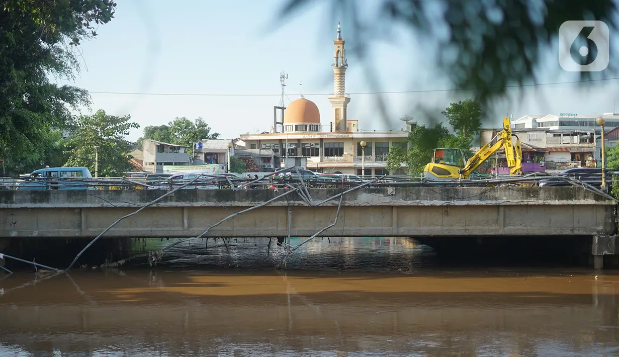 Warga berjalan di samping pagar jembatan yang rusak di kawasan Bukit Duri, Jakarta, Jumat (21/2/2020). Pagar yang rusak akibat penanganan sampah banjir tersebut hingga kini belum juga diperbaiki. (Liputan6.com/Immanuel Antonius)