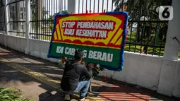 Isi karangan bunga tersebut menyatakan kekecewaan para nakes terhadap pemerintah dan meminta untuk menghentikan pembahasan RUU Kesehatan Omnibuslaw. (Liputan6.com/Faizal Fanani)