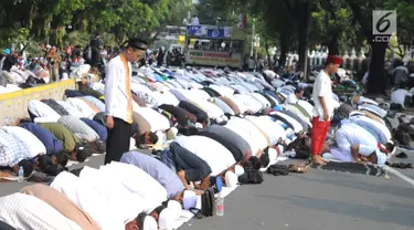 Massa pendukung pasangan capres-cawapres Prabowo Subianto dan Sandiaga Uno melakukan salat asar di Jalan Medan Merdeka Barat, Jakarta, Kamis (27/6/2019). Aksi tersebut dilakukan jelang putusan perselisihan hasil pemilihan umum (PHPU) Pilpres 2019 di Gedung MK. (merdeka.com/Arie Basuki)