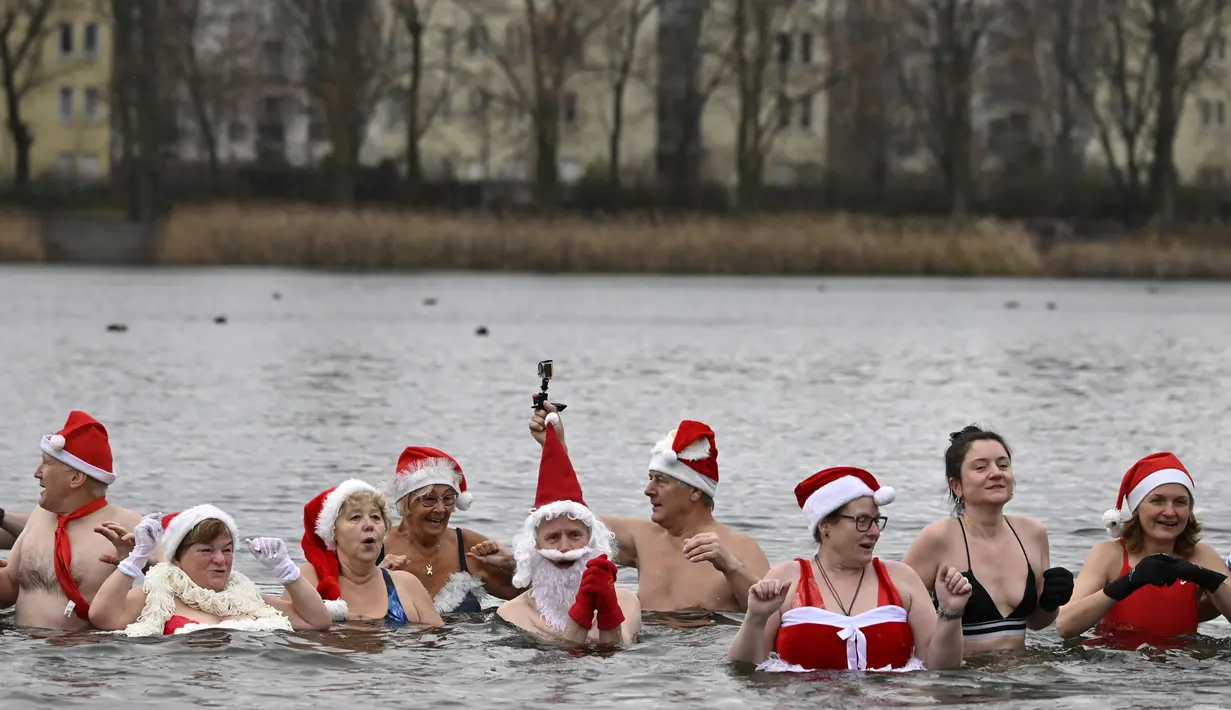 Anggota klub renang "Berliner Seehunde" (Berlin Seals) berendam di Danau Orankesee, Berlin, Minggu (25/12). Kegiatan yang sudah menjadi tradisi ini merupakan bagian dari perayaan tradisional Natal bagi warga Berlin. (Tobias SCHWARZ / AFP)