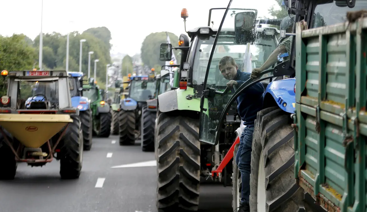 Sejumlah peternak sapi perah menaiki traktor mereka menuju jalan tol atau jalan bebas hambatan untuk melakukan aksi protes di Battice, Belgia, Kamis (30/7/2015). Aksi protes tersebut berkaitan dengan rendahnya harga jual susu. (REUTERS/Francois Lenoir)