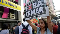 Seorang wanita membawa poster bertuliskan “Keluarkan Temer!” dalam unjuk rasa di Sao Paulo, Brasil, Rabu (2/8). Demonstrasi tersebut bertujuan untuk melengserkan Presiden Brasil Michel Temer yang diduga terkait kasus korupsi. (AP/Andre Penner)