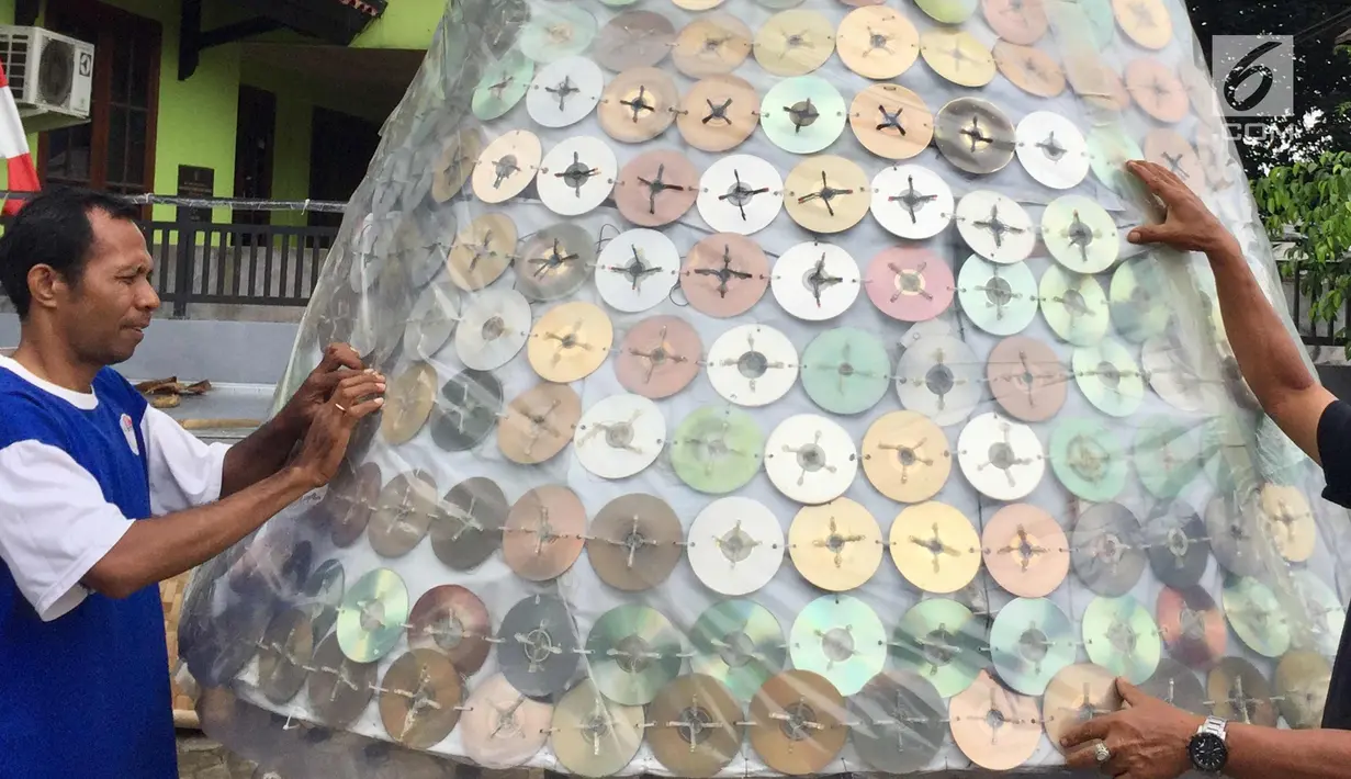Jemaat Gereja Kristen Pasundan Jemaat Depok mengecek pohon Natal berbahan dasar keping CD bekas, Jakarta, Selasa (19/12). Pohon Natal setinggi 5,5 meter terbuat dari 1.100 keping CD bekas dan 4.400 hiasan lampu. (Liputan6.com/Immanuel Antonius)