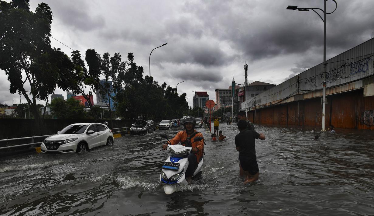 Pengendara motor berusaha menerobos genangan air di ruas Jalan Satrio, Grogol, Jakarta Barat, Rabu (29/1/2025). (merdeka.com/Arie Basuki)
