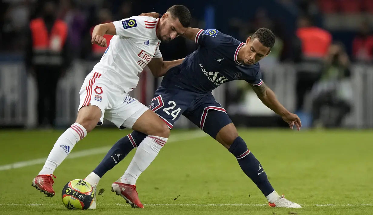 Gelandang Olympique Lyon Houssem Aouar dan bek Paris Saint-Germain (PSG), Thilo Kehrer berebut bola dalam laga pekan keenam Liga Prancis di Stadion Parc des Princes, Senin (20/9/2021) dini hari WIB. PSG menang dengan skor tipis 2-1. (AP Photo/Francois Mori)