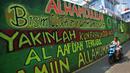 Pengendara melintasi mural bernuansa Islami di Gang Pelangi, kawasan Kalibata, Jakarta, Jumat (23/4/2021). Mural bernuansa Islami tersebut dibuat untuk menghiasi dan meramaikan pintu masuk gang sekaligus mengingatkan masyarakat untuk selalu beribadah dan bershalawat (Liputan6.com/Herman Zakharia)