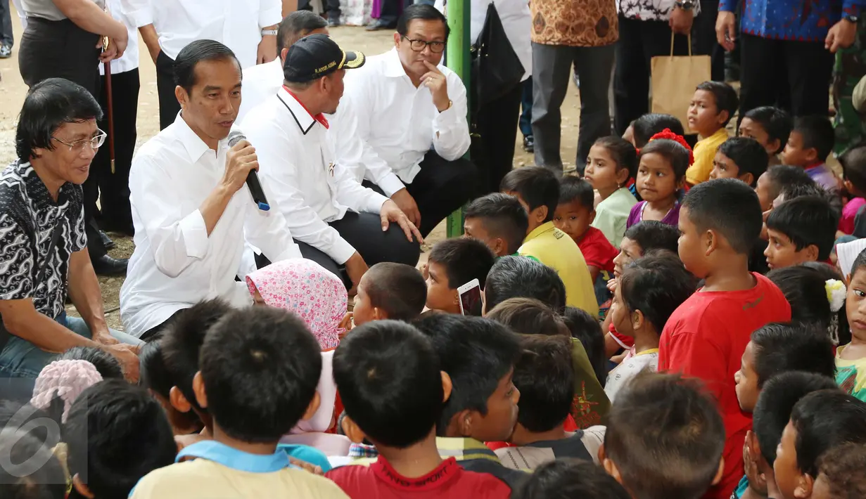Presiden Joko Widodo (Jokowi) berdialog dengan para anak saat meninjau tenda pengungsian korban gempa Aceh di Pidie Jaya, Jumat (9/12). Dalam kunjungan tersebut, Jokowi membagikan buku tulis untuk anak-anak. (Liputan6.com/Angga Yuniar)