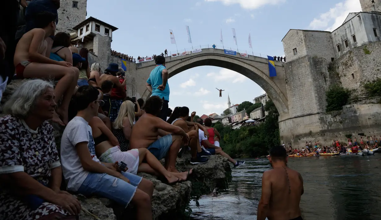 Penonton menyaksikan seorang peserta melompat dari Jembatan Old Mostar pada kompetisi menyelam tradisional ke-452 di Mostar, Bosnia, 29 Juli 2018. Ini merupakan kompetisi selam tahunan yang menjadi salah satu daya tarik Bosnia. (AP/Amel Emric)