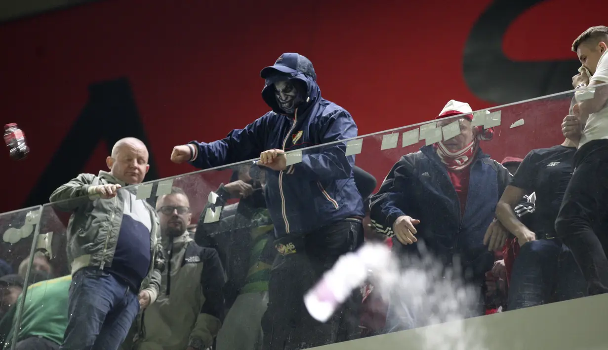 Seorang penggemar Polandia melempar botol ke pendukung Albania pada lanjutan Grup I Kualifikasi Piala Dunia 2022 Zona Eropa, di Air Albania Stadium, Rabu (13/10/2021) dini hari WIB. Kemenangan Polandia 1-0 atas Albania diwarnai aksi pelemparan botol oleh suporter. (AP Photo/Franc Zhurda)