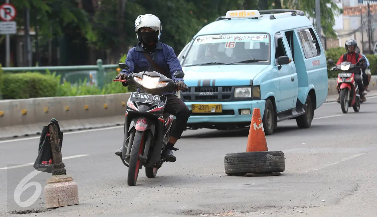 Kendaraan menghindari penanda lubang di Jalan Otista Raya, Jakarta, Rabu (22/2). Kondisi tersebut berbahaya bagi pengguna jalan, khususnya pengendara sepeda motor yang melintas saat malam hari. (Liputan6.com/Immanuel Antonius)