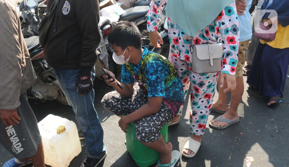 Seorang anak ikut antre untuk membeli minyak goreng curah pada distributor di Jalan MA Salmun, Bogor, Kamis (31/3/20222). Di tempat ini pembelian dibatasi hanya satu jerigen atau berisi 16 liter dengan harga Rp 256.000 atau Rp 16.000 per liter. (merdeka.com/Arie Basuki)
