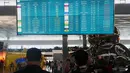 Calon penumpang berjalan melewati papan informasi yang menunjukkan penerbangan terganggu di Bandara Internasional Soekarno-Hatta di Tangerang, Indonesia, Minggu, 6 September 2026. (AP Photo/Tatan Syuflana)