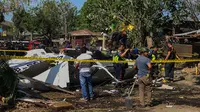 Penyelidik berdiri di dekat puing-puing Helikopter bell 429 yang membawa kepala polisi Filipina setelah jatuh di Kota San Pedro, selatan Manila, Kamis (5/3/2020). Tidak ada yang tewas dalam kejadian tersebut, dan semua penumpang dibawa ke rumah sakit untuk menjalani perawatan. (AFP)