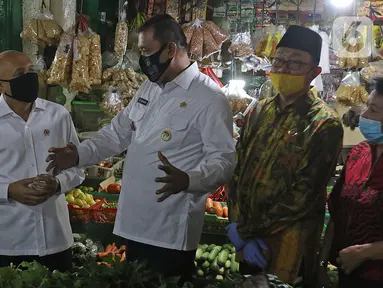 Menteri Koperasi dan UKM Teten Masduki (kiri) berbincang dengan Wakil Wali Kota Bekasi Tri Adhianto usai mengunjungi Pasar Kranggan, Bekasi, Jawa Barat, Jumat (19/6/2020). Teten meninjau restrukturisasi pinjaman/pembiayaan LPDB-KUMKM kepada Koperasi Pasar Kranggan. (Liputan6.com/Herman Zakharia)