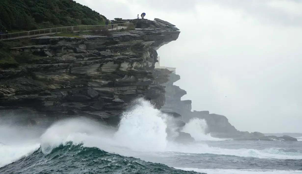 Orang-orang menonton dari atas tebing saat ombak besar menghantam pantai di Sydney, Australia, 24 Mei 2022. (AP Photo/Mark Baker)