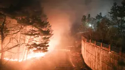 Kebakaran hutan yang melanda di dekat sebuah kota di Sokcho, Korea Selatan (4/4). Kantor berita Yonhap melaporkan, ada 45 helikopter, 77 kendaraan pemadam, dan 13.000 personel dikerahkan untuk mengatasi kebakaran hutan tersebut. (AFP Photo/South Korea Out)