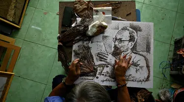 Seniman Le Van Nghia mengerjakan lukisan mendiang pemimpin revolusi Vietnam Ho Chi Minh yang terbuat dari daun teratai kering di rumahnya di provinsi Dong Thap, 22 Januari 2021. Le Van Nghia berhenti dari pekerjaannya sebagai tukang kayu untuk mengejar impian masa kecil. (Manan VATSYAYANA/AFP)