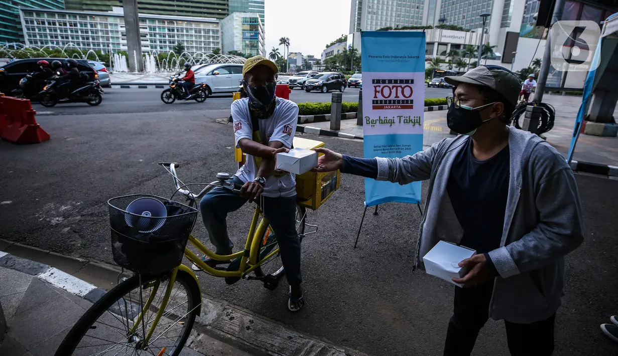 Pewarta Foto membagikan takjil kepada pejalan kaki di Kawasan Bundaran HI, Jakarta, Selasa (20/4/2021). Kegiatan berbagi takjil yang digagas oleh Pewarta Foto Indonesia Jakarta (PFIJ) ini dilaksanakan setiap hSelasa dan Jumat selama bulan Ramadhan sebagai bentuk solidaritas (Liputan6.com/JohanTallo)