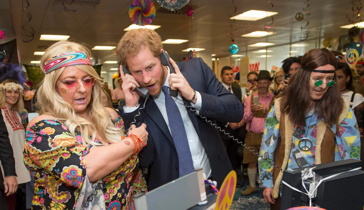Pangeran Harry mengangkat dua telepon sekaligus saat menjadi broker dalam acara amal tahunan ICAP di London, Rabu (7/12). Pangeran Harry menjadi broker dadakan untuk mengumpulkan dana amal dari 60 kantor di seluruh dunia. (REUTERS/Geoff Pugh/Pool)