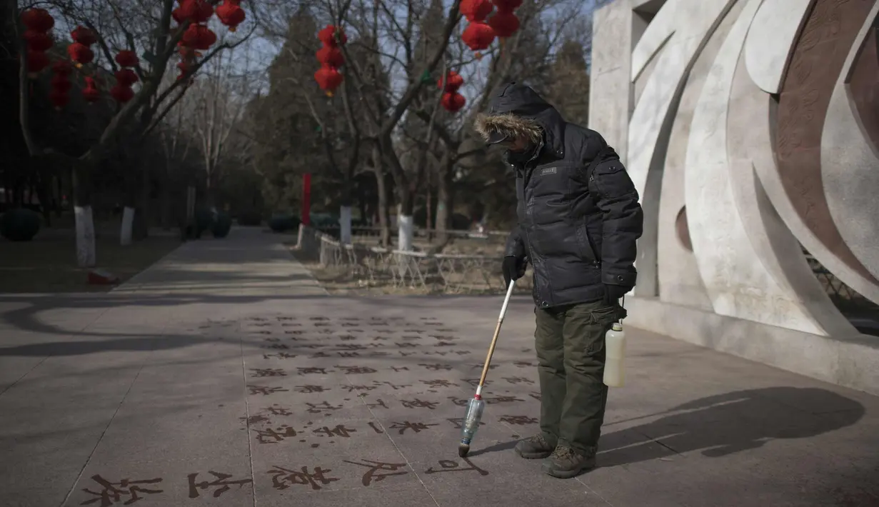Seorang pria menulis sebuah puisi di lantai dengan air di Ditan Park di Beijing (1/2). Tahun Baru Imlek jatuh pada 16 Februari tahun ini, dengan perayaan yang berlangsung selama seminggu di China. (AFP Photo/Nicolas Asfouri)
