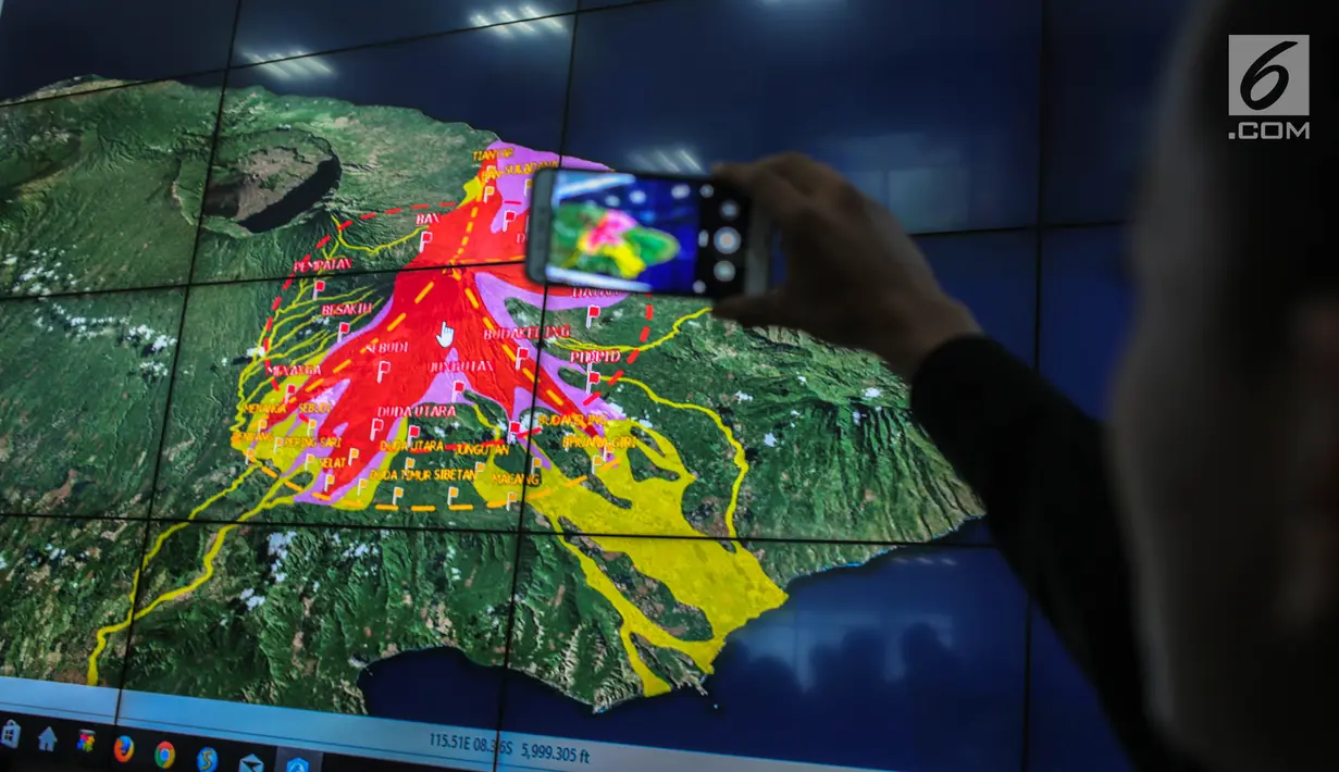 Petugas mengambil gambar kondisi Gunung Agung Bali yang berada di layar monitor di Gedung BNPB, Jakarta, Senin (25/9). Sutopo mengajak seluruh masyarakat untuk melawan hoax tentang meletusnya Gunung agung. (Liputan6.com/Faizal Fanani)