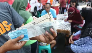 Warga menunjukkan STNK yang baru diperpanjang di gerai Samsat Keliling Car Free Day, Jakarta, Minggu (21/10). Layanan pembayaran pajak Surat Tanda Nomor Kendaraan (STNK) bisa dilakukan tanpa membawa salinan atau BPKB. (Liputan6.com/Angga Yuniar)