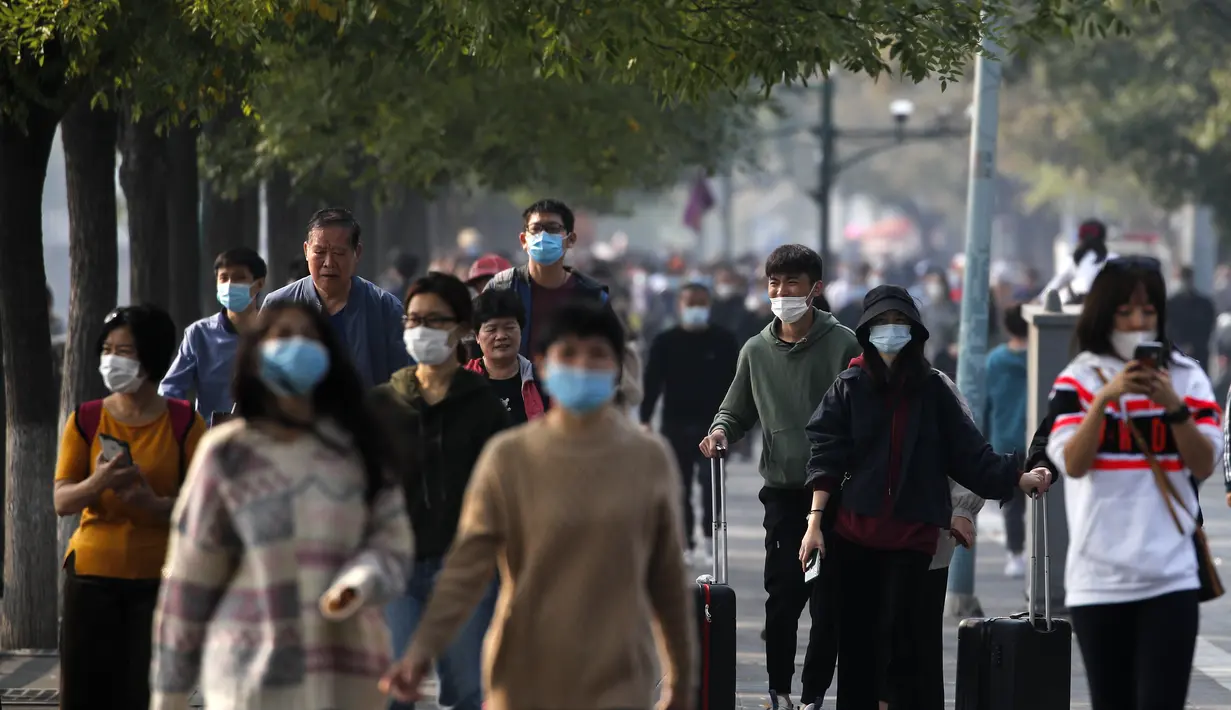 Pengunjung yang mengenakan masker wajah untuk membantu mengekang penyebaran virus corona berjalan di sepanjang Kota Terlarang selama liburan Hari Nasional selama seminggu di Beijing, Rabu, (7/10/2020). (AP Photo/Andy Wong)