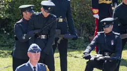 Anggota The Rifles dibantu rekanya usai terjatuh menjelang pemakaman Pangeran Philip di luar Kapel St George, Windsor, Inggris (17//4/2021). Pemakaman ini menerapkan protokol kesehatan, semua tamu termasuk Keluarga Kerajaan, harus mengenakan masker dan duduk terpisah. (Arthur Edwards/Pool via AP)