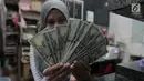 Petugas menunjukkan pecahan uang dolar Amerika di salah satu gerai penukaran mata uang asing di Jakarta, Rabu (5/9). Nilai tukar Rupiah di pasar spot menguat tipis 0,06 persen ke Rp 14.926 per dollar Amerika. (Merdeka.com/Imam Buhori)